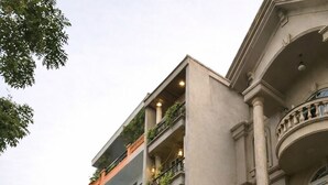 Een meerlaags gebouw met balkons, een opvallend 'Olie Home' bord en een hekwerk.