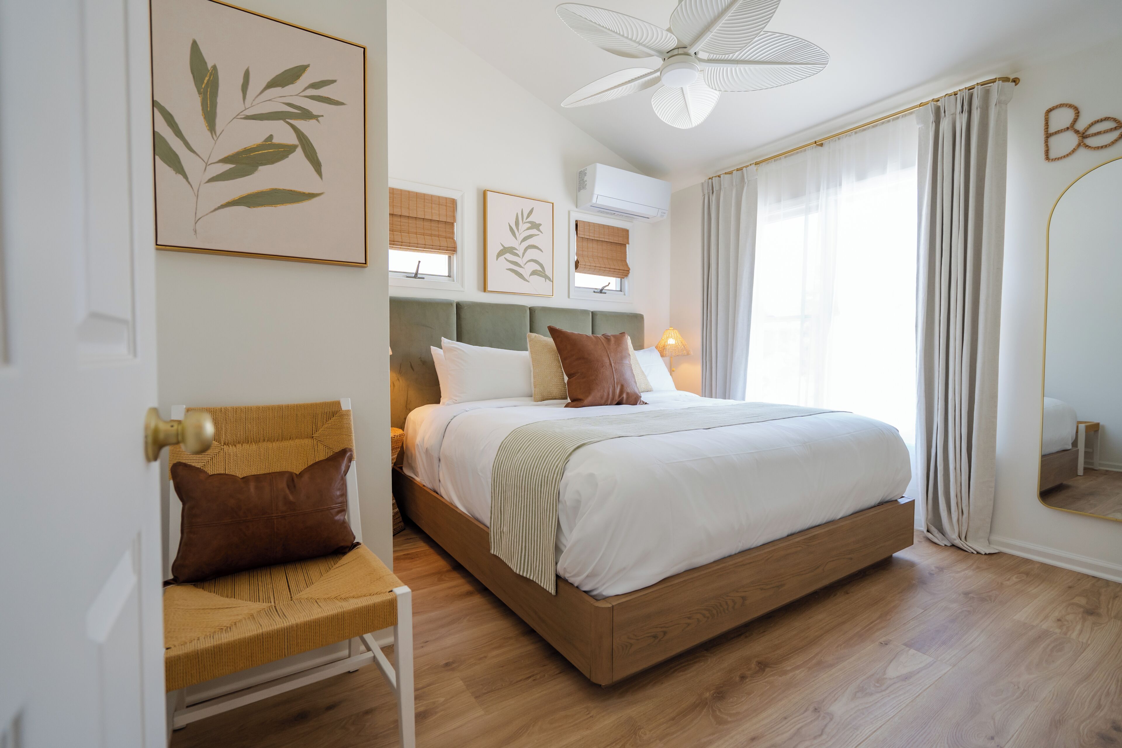 A bedroom with a bed, a chair, a ceiling fan, and a wall-mounted air conditioner.