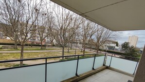 Ein Balkon mit Blick auf einen Park, Bäume und Gebäude.