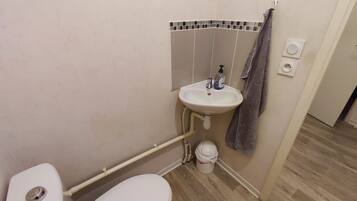 A small bathroom with a toilet, a sink, and a towel hanging on the wall.