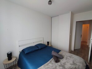 A bedroom with a bed, a bedside table, and a wardrobe. - To complete (Chenôve)