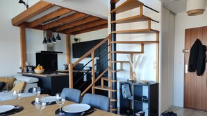 A modern living space with a dining area, kitchen, and staircase. - Duplex moderne, chaleureux au calme à Toison d'or (Dijon)