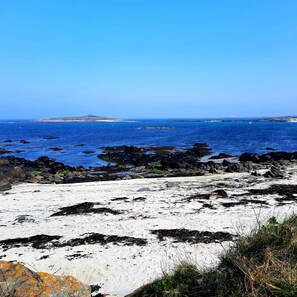 Una playa costera con afloramientos rocosos y un cielo azul despejado.