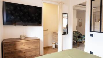 Ein Schlafzimmer mit einem Bett, einem Schminktisch, einem Fernseher und einem durchgehenden Türspalte einsehbaren Badezimmer.