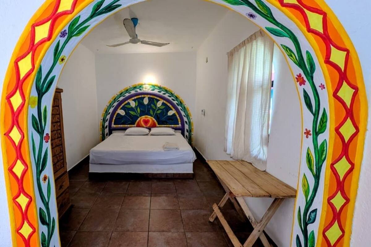 A bedroom with a bed, a ceiling fan, and a small wooden table.