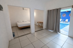 A hotel room with a bed, a small table, and a view of a swimming pool. - Kaia Beach Hotel (Puerto Escondido)