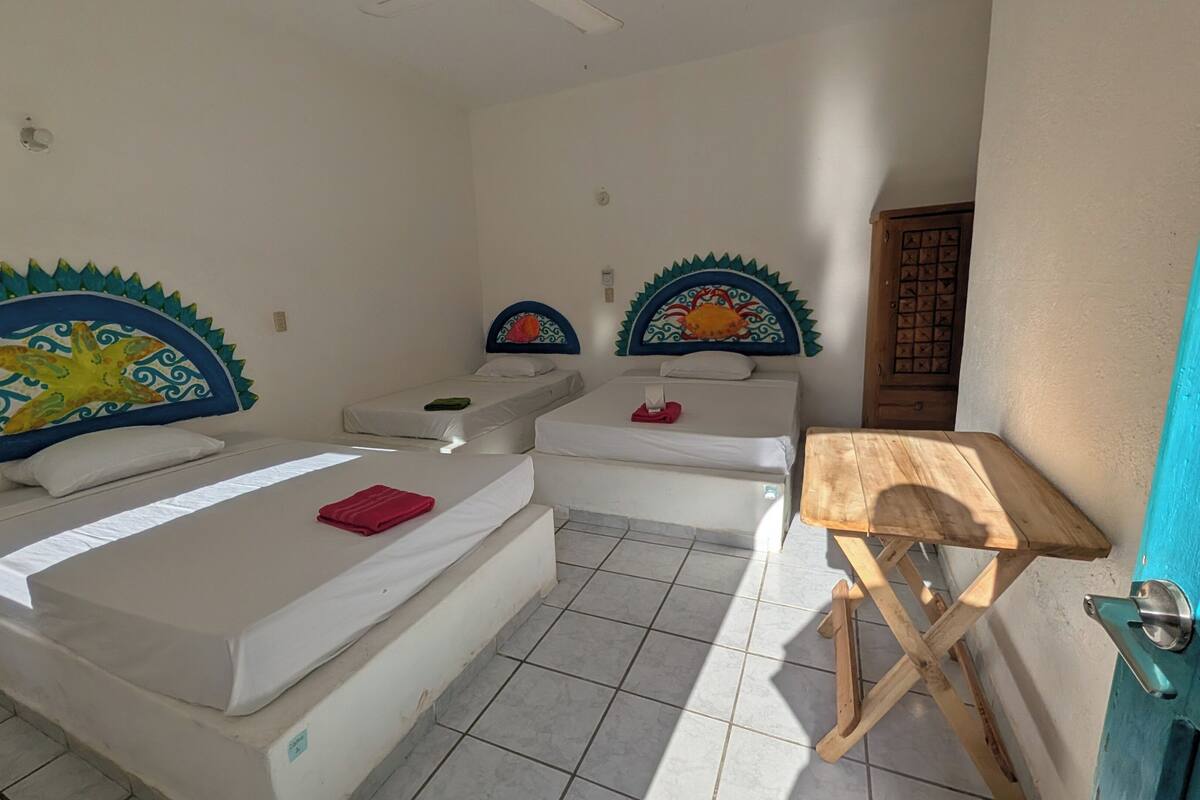 A hotel room with two beds, a wooden table, and decorative headboards.