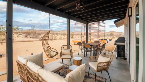 Eine Terrasse im Freien mit Korbmöbeln, einem Tisch und Stühlen mit Blick auf eine Wüstenlandschaft.
