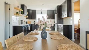 Eine moderne Küche mit dunklen Schränken, einem Holztisch und einer Vase mit Blumen.
