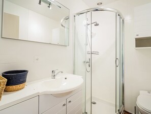 Ein modernes Badezimmer mit einer Duschkabine, einem weißen Waschbecken und einer Toilette.