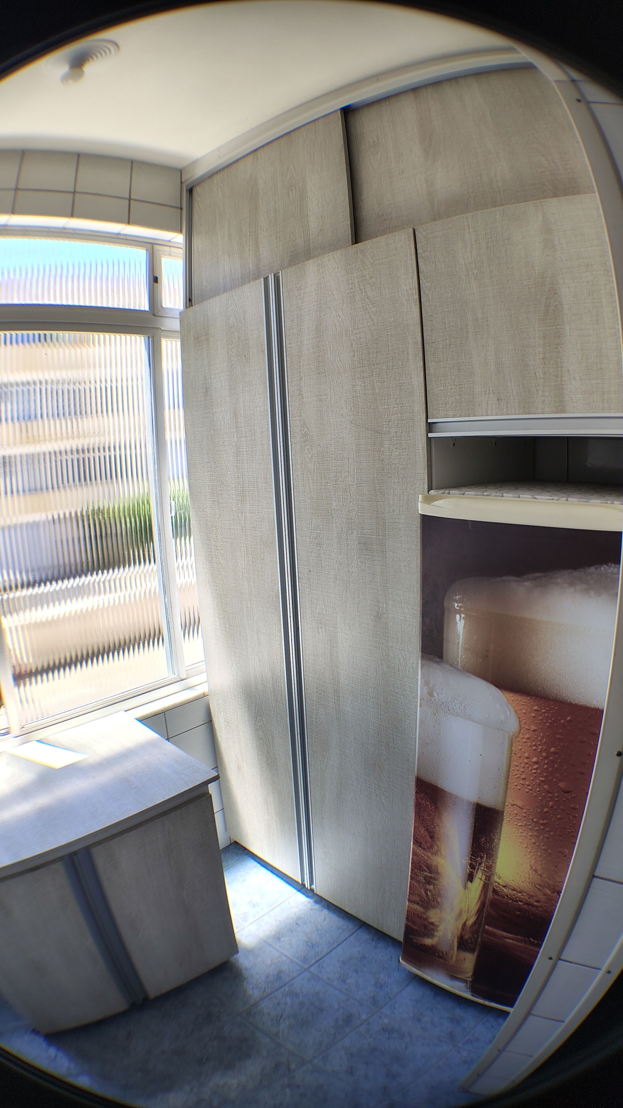 A compact, modern room with a curved ceiling, a built-in bench, and a large window with blinds.