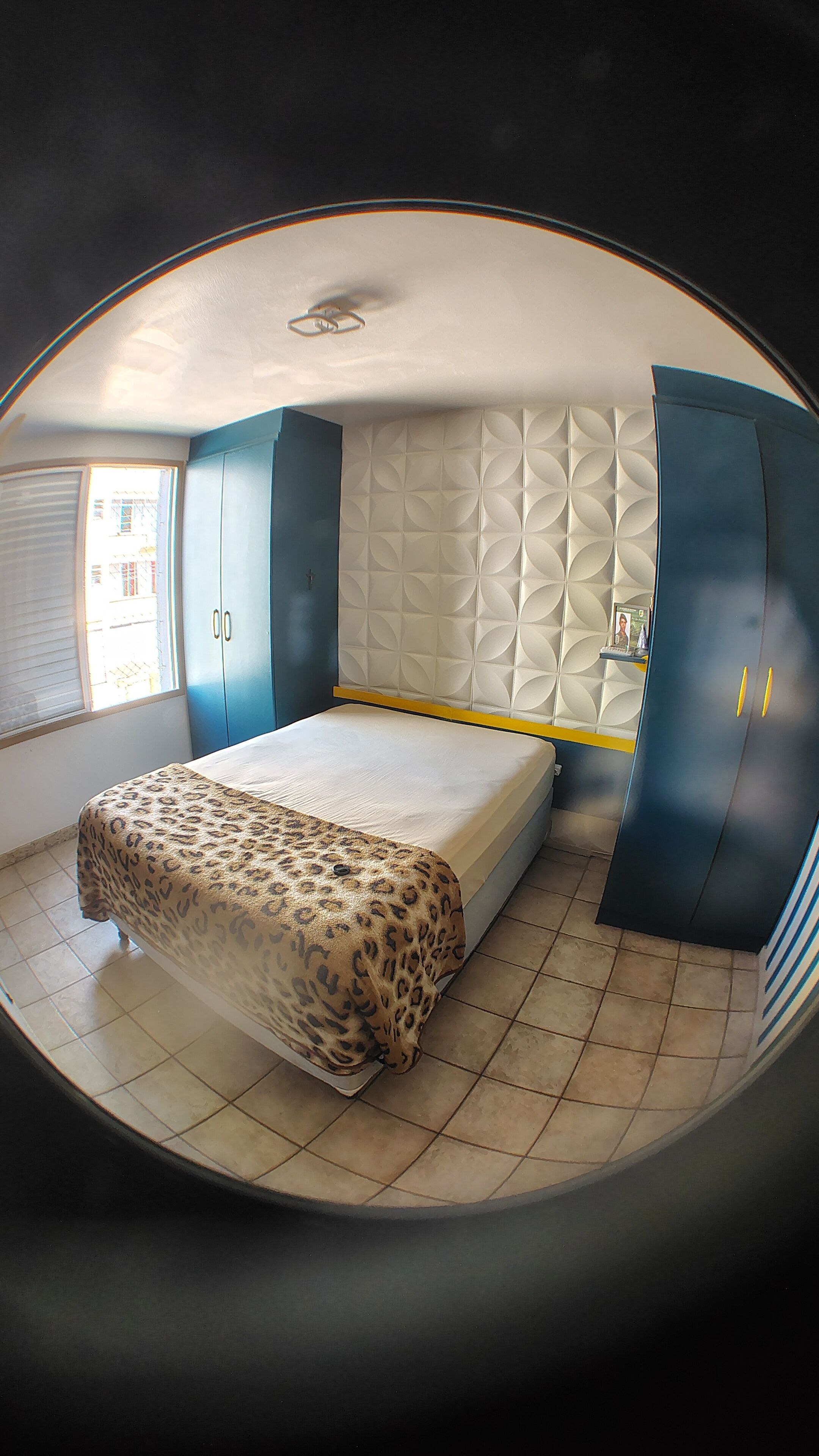 A bedroom with a bed, a wardrobe, and a headboard with a geometric pattern.