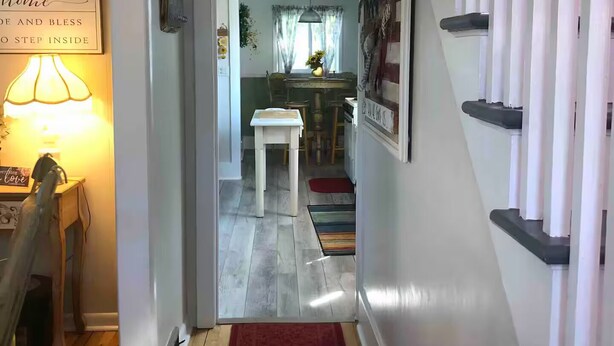 A hallway leading to a dining area with a table and chairs, a red rug, and a sign on the wall. - The Happy House! (Wakefield)