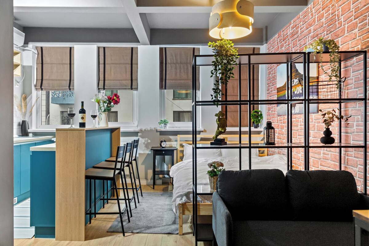 Un interior moderno con cocina, comedor y sala de estar separados por una división de metal negro.