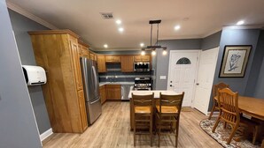 A modern kitchen with wooden cabinets, stainless steel appliances, and a dining area with wooden chairs. - Beautiful 4-bedroom 2 bath residence. (Union)