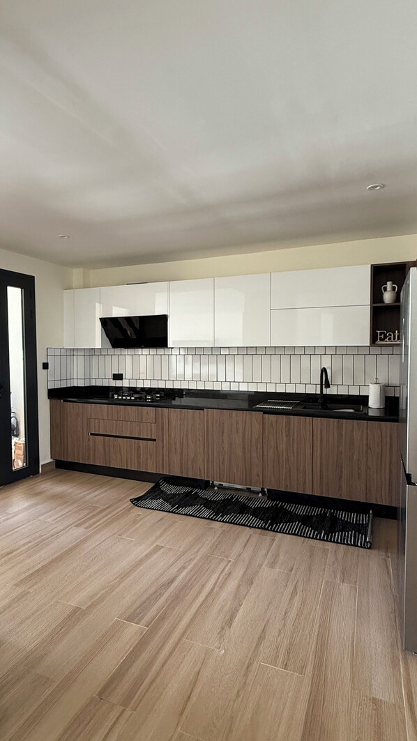A modern kitchen with wooden cabinets, a black countertop, and a tiled backsplash.