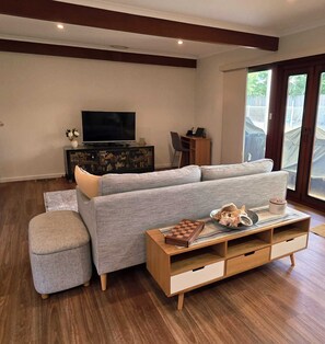Una sala de estar moderna con un sofá gris, una mesa de centro de madera y un televisor sobre un mueble negro.