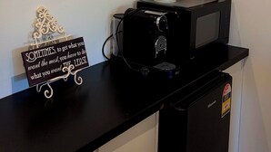 Uma bancada de cozinha com uma cafeteira, um micro-ondas e um vaso decorativo com plantas secas.