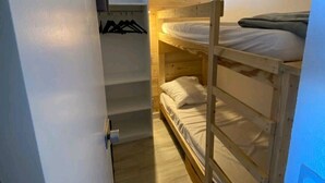 Een kleine, smalle kamer met een stapelbed en een houten trap.