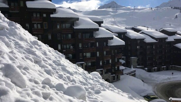 Een berglandschap bedekt met sneeuw, met een complex van gebouwen.