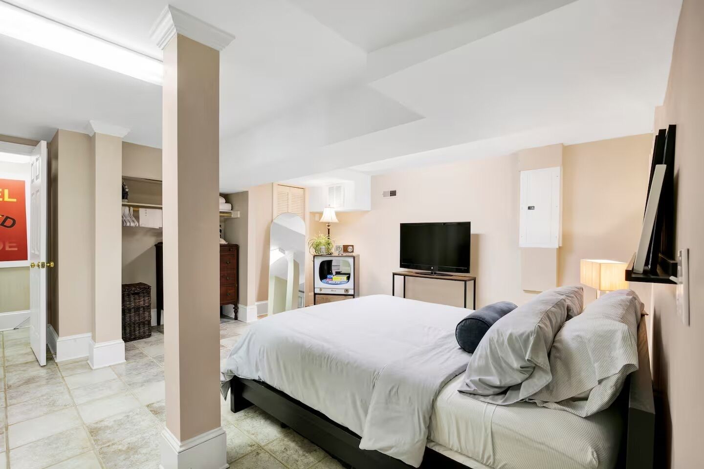 A modern hotel room with a large bed, a TV, a desk, and a wardrobe.