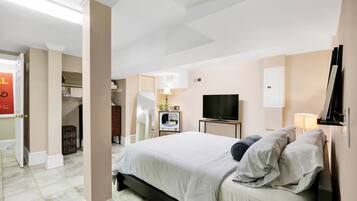 A modern hotel room with a large bed, a TV, a desk, and a wardrobe.