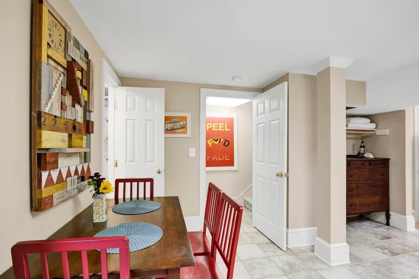A dining area with a wooden table, red chairs, and a wall-mounted clock.