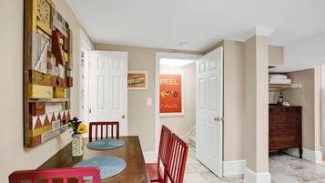 A dining area with a wooden table, red chairs, and a wall-mounted clock.