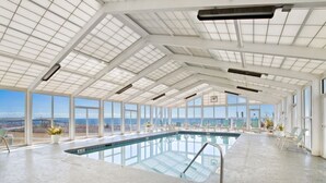 An indoor swimming pool with clear views of the ocean, large windows, and a high ceiling with skylights. - Perdido Sun 608 with Balcony (Perdido Key)