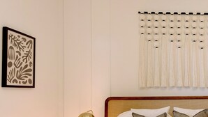 Un llit ben fet amb capçalera, una làmpada de nit i una obra d'art emmarcada a la paret.
