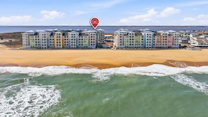 Ett hotell vid stranden med färgglada byggnader, en sandstrand och havet.