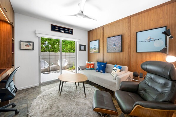 A modern living room with a sofa, a leather armchair, a round table, and a ceiling fan. - Whiskey Rocks 2.0 (Palm Springs)