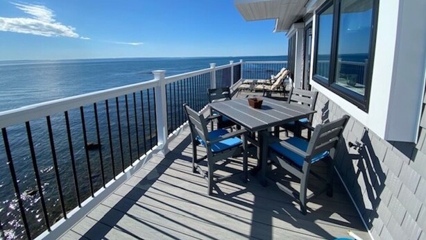 En terrasse med et bord og stole, med udsigt over havet.