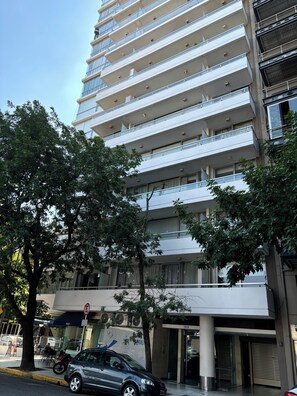 A multi-story building with balconies, a car parked in front, and trees in the foreground. - Decó Apart by Beauty Smart Hotel (Buenos Aires)