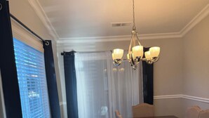 A dining room with a dark wooden table and chairs, a chandelier, and a view through a window with blinds. - Soothing 3-bedroom house with AC in charming Merced (Merced)