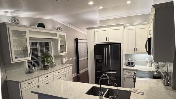 A modern kitchen with white cabinetry, a stainless steel refrigerator, a built-in oven, and a granite countertop. - Soothing 3-bedroom house with AC in charming Merced (Merced)
