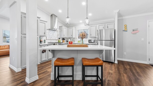 A modern kitchen with white cabinets, stainless steel appliances, and a central island with stools. - Game On! River Getaway Sleeps 10 in Bullhead City (Bullhead City)