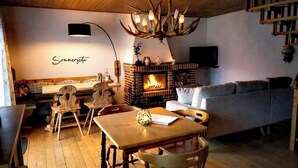 A cozy living room with a fireplace, wooden furniture, and a chandelier.