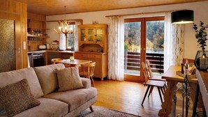A cozy living room with a sofa, dining table, and kitchen area.