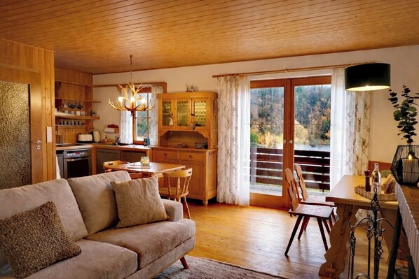 A cozy living room with a sofa, dining table, and kitchen area.