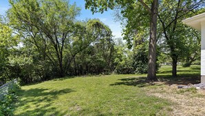 A grassy backyard with trees and a white building.