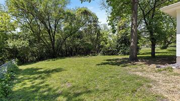 A grassy backyard with trees and a white building.