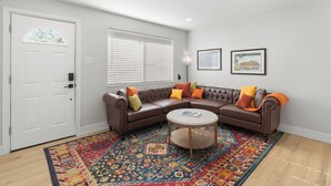 A living room with a brown sectional sofa, a round coffee table, and a colorful rug.