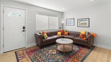 A living room with a brown sectional sofa, a round coffee table, and a colorful rug.