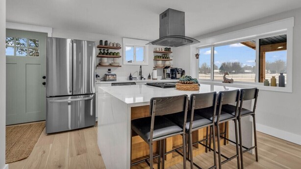 Een moderne keuken met een groot eiland, roestvrijstalen apparatuur en uitzicht op de omgeving.
