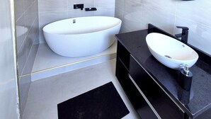 Une salle de bain moderne avec une baignoire sur pieds, un miroir rond et un meuble-lavabo noir avec un vasque blanche.