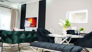 Un salon moderne avec un canapé, une table à manger dressée pour deux personnes, un téléviseur et un miroir au mur.