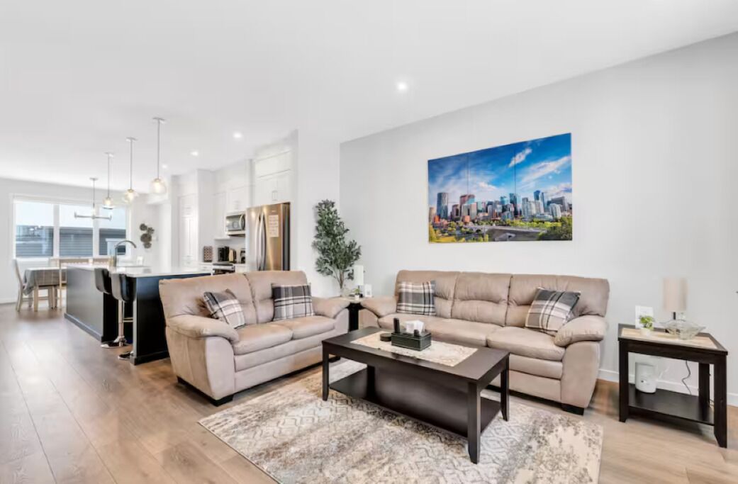 A modern living room with a sofa set, coffee table, and a painting of a cityscape on the wall.