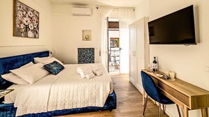 Een slaapkamer met een bed, een bureau, een televisie en uitzicht op een buitenruimte.
