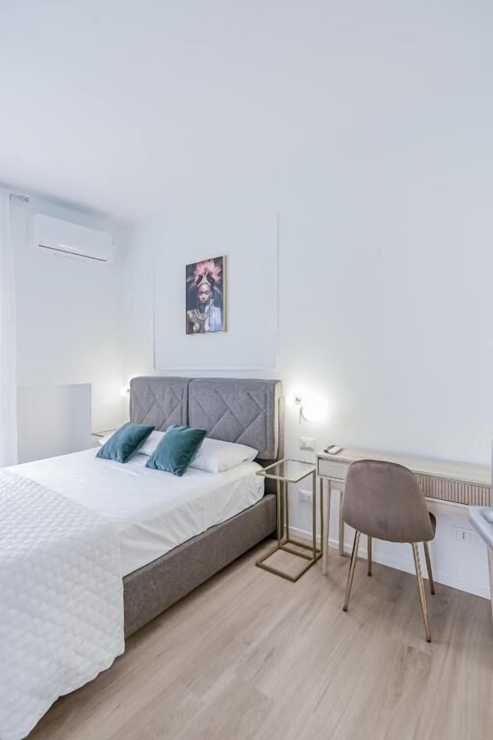 Une chambre moderne comprenant un lit, une table de chevet, une chaise et une œuvre d’art accrochée au mur.